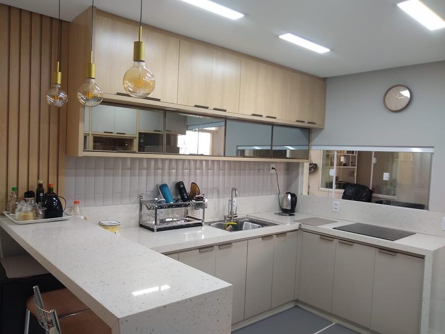 Cozinha em U com bancada de granito claro e armários planejados amadeirados, feita pela U.P.FÉ